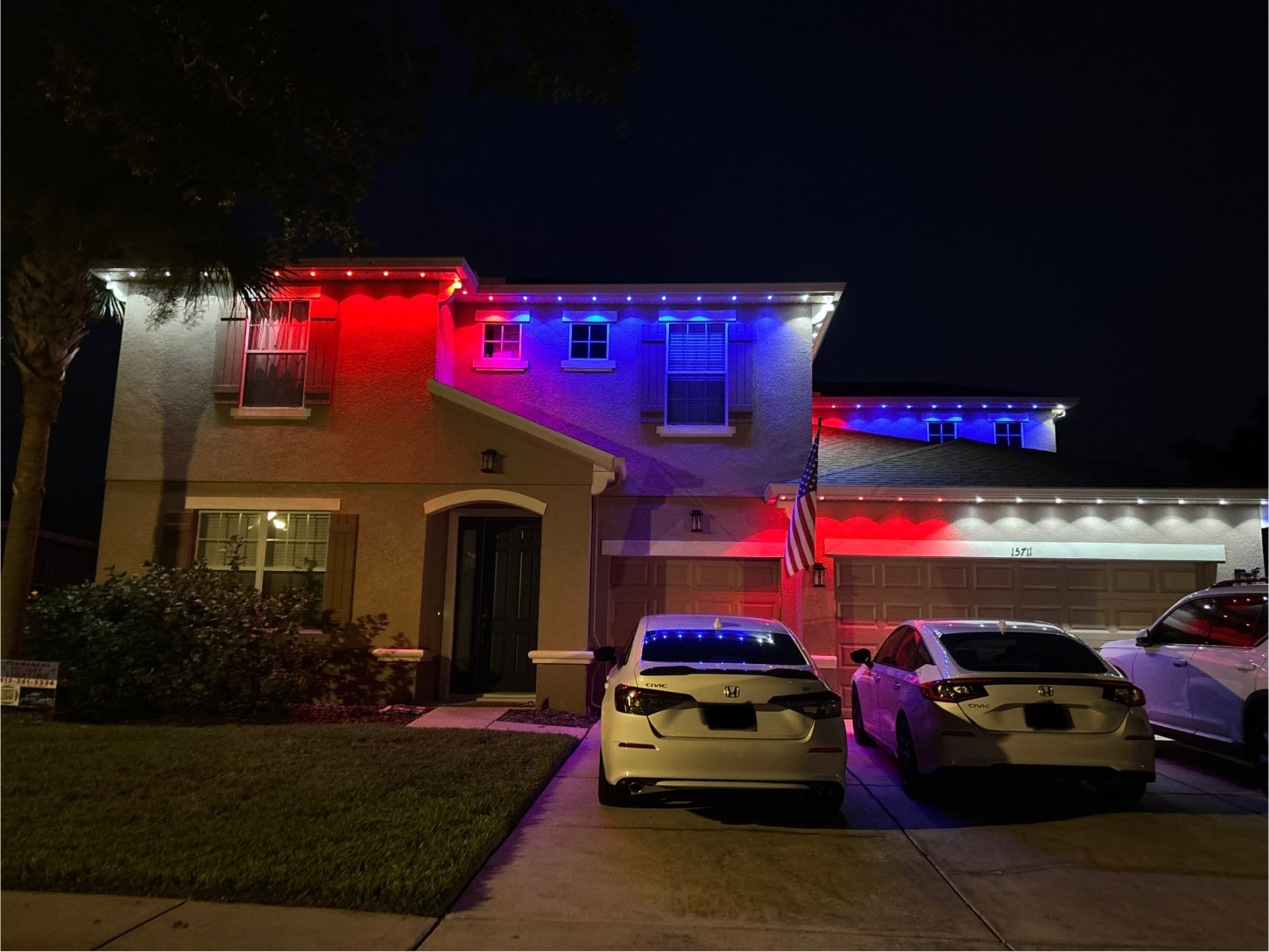 Two-story home with red, white and blue permanent LED roofline lighting at night