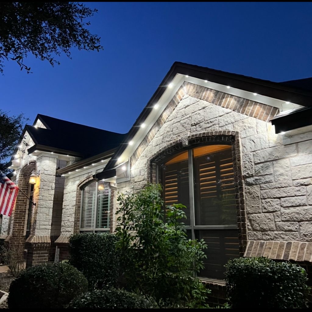 Stone home with warm white permanent LED accent lighting at dusk
